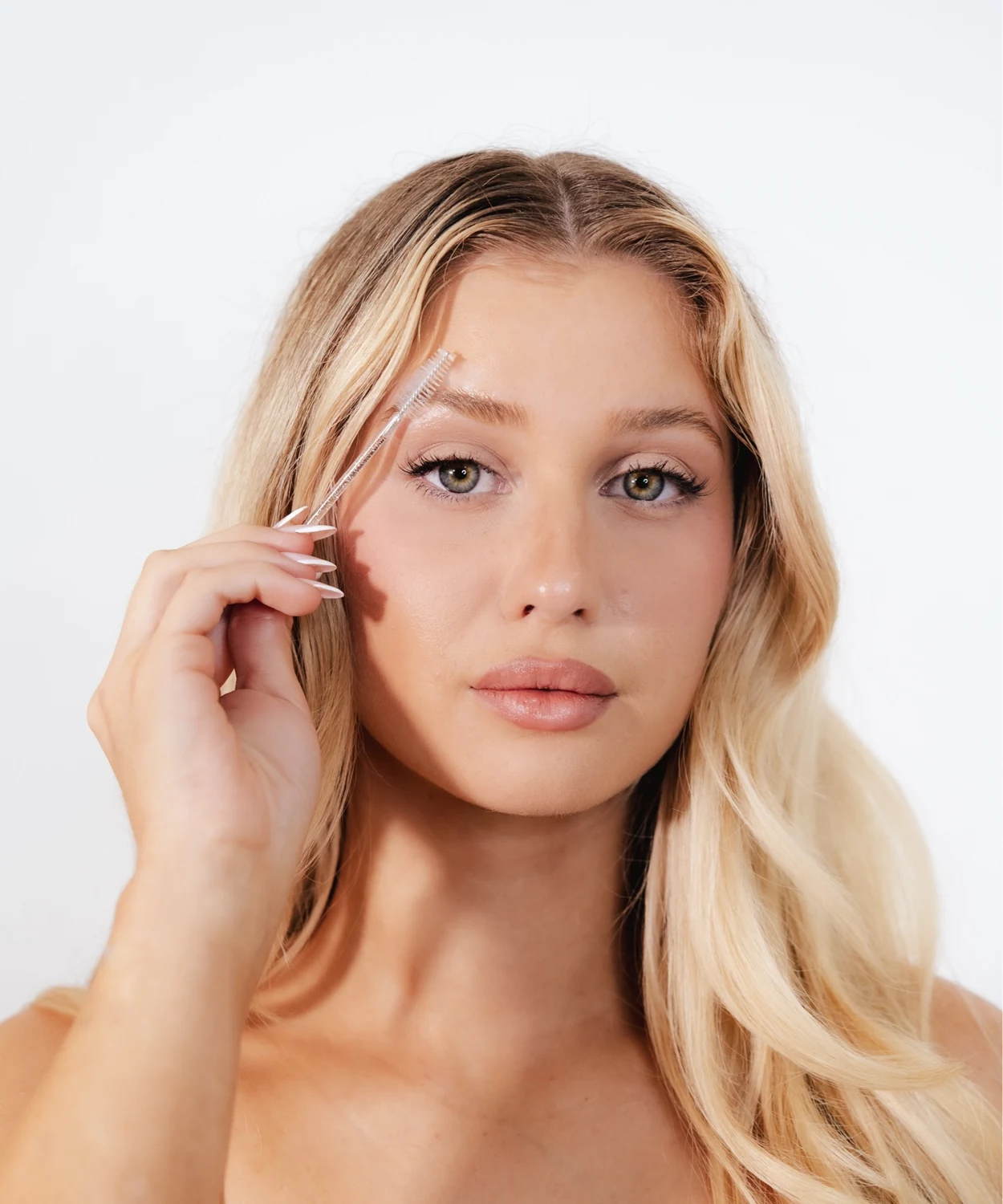 A client brushing through her freshly laminated brows with a spoolie